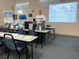 A man standing in front of a classroom with many chairs.