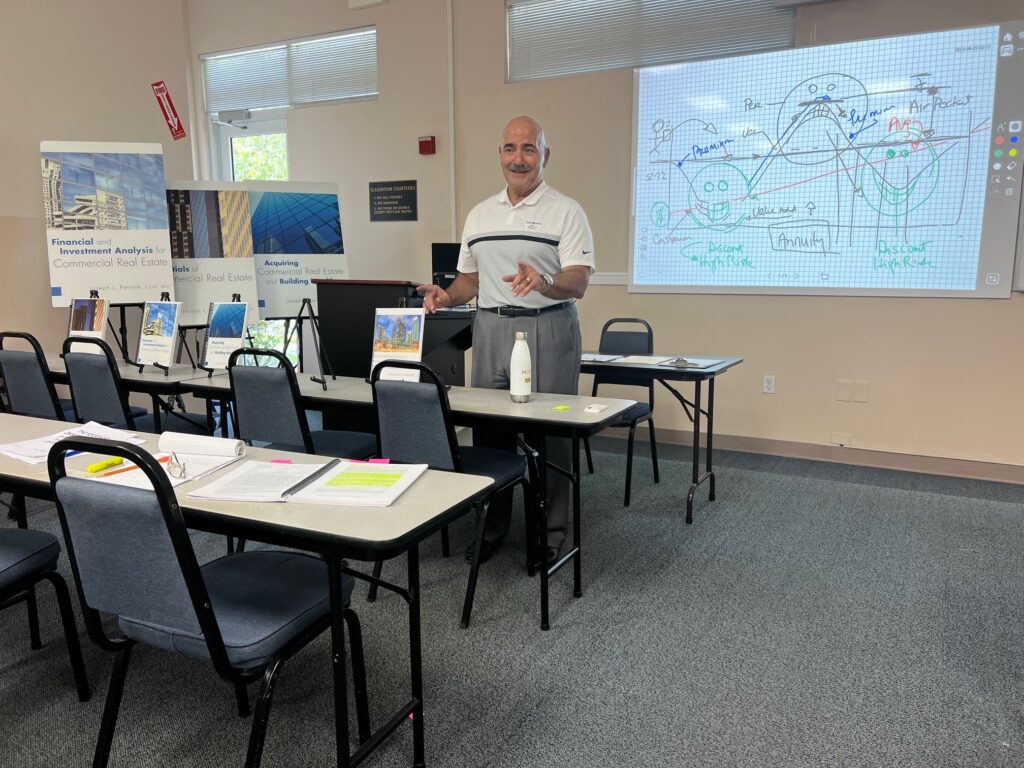 A man standing in front of a classroom with many chairs.